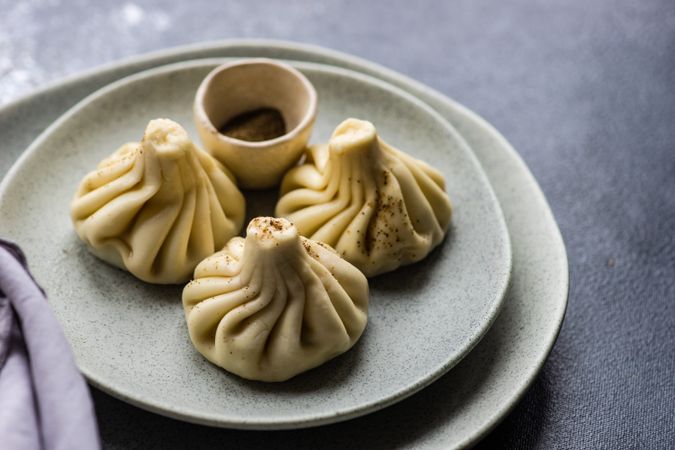 Grey plate with three Georgian khinkali dumplings with copy space