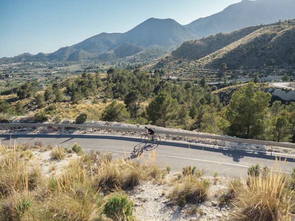healthy man riding a bicycle on a mountain road in a sunny day