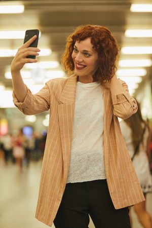 Red haired young woman using smartphone at station