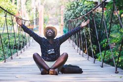 Man sitting on wooden footbridge raising his arms