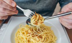 Hands of man eating spaghetti with worms