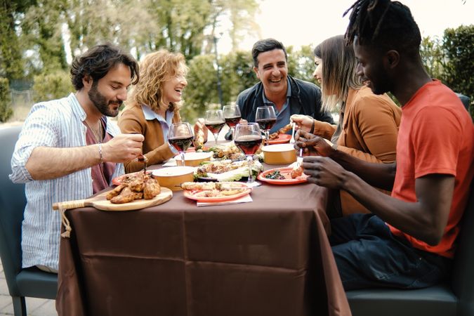 A group of friends are enjoying a meal together at a picnic table set in the countryside