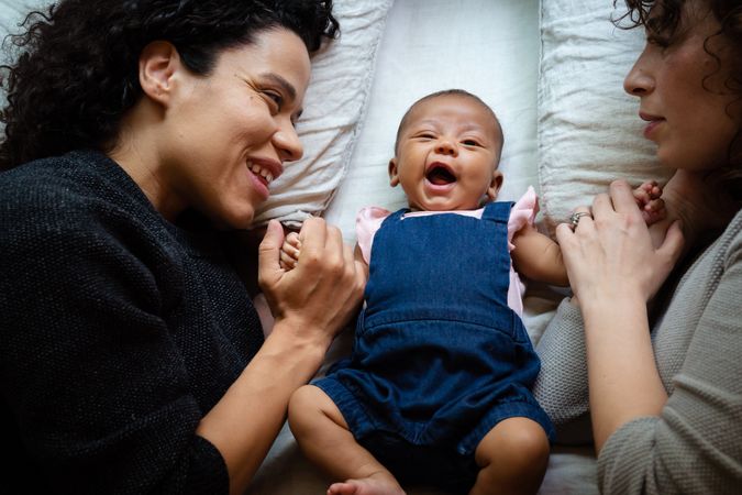 Baby girl lying down and yawning with mothers