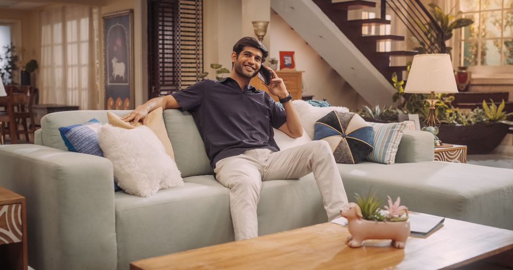 Young Indian Man Talking on Phone with Family, Friends or Clients. Smiling, Happy and Charming, Does Remote Work of Virtual Collaboration, Customer Support from Home.