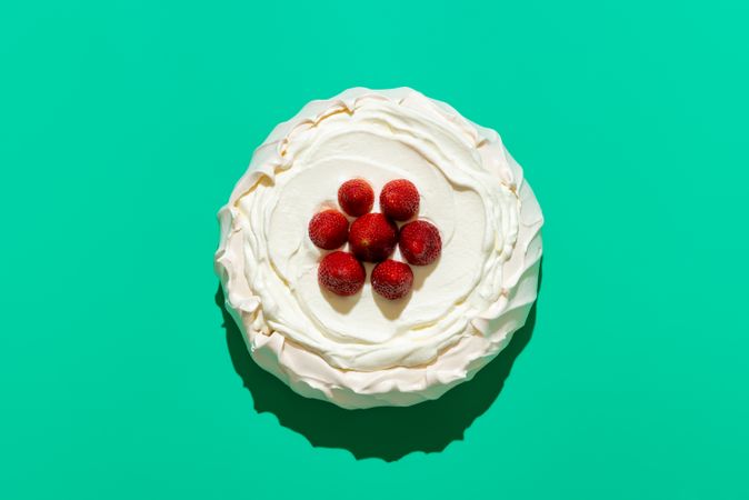 Pavlova with strawberries, above view on a green background