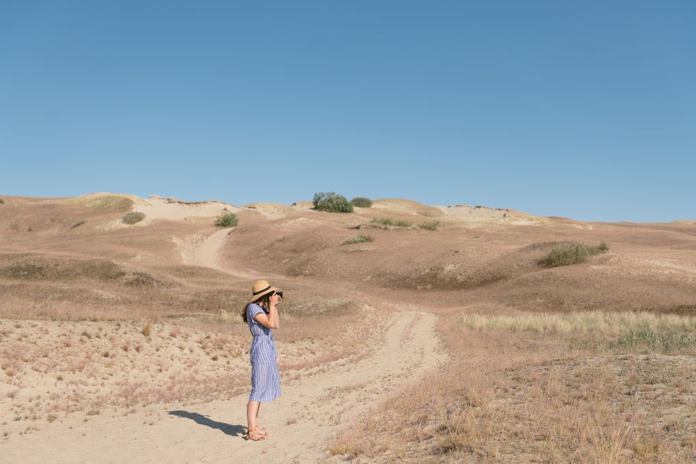 Young female photographer on dry field
