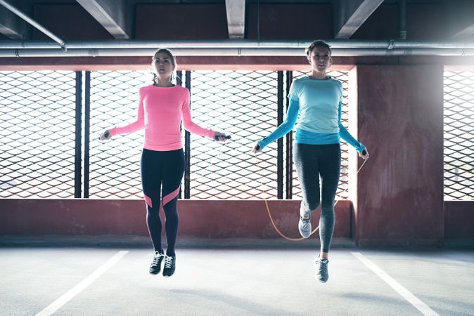 Two fit females skipping rope near window
