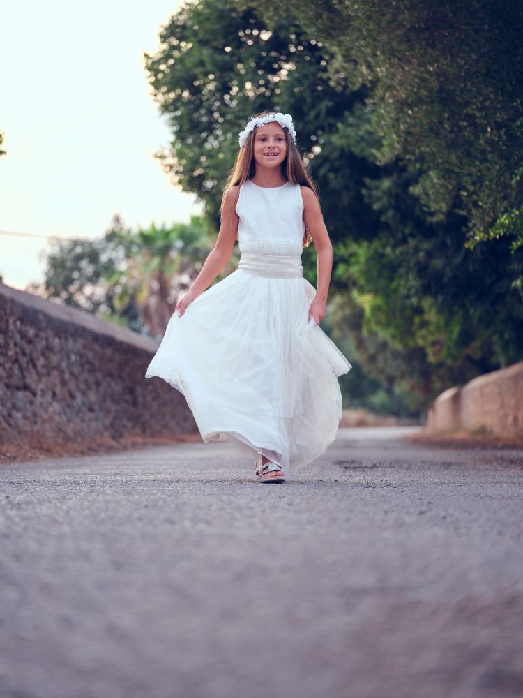Elegant girl in white gown walking along alley