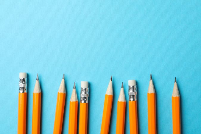 Pencils in a row on blue background with copy space