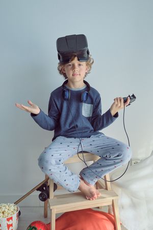 Adorable boy on stool stepladder with VR goggles on head