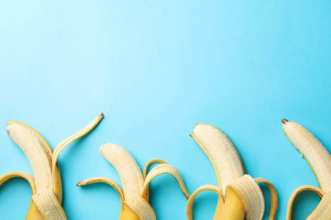 Opened bananas on blue background. Fresh fruit