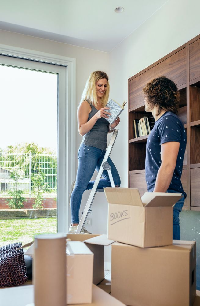 Couple unpacking boxes and placing books