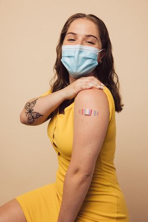 Young woman showing her arm with bandage after vaccination