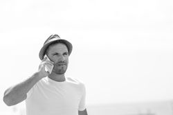 Monochrome shot of male speaking on phone outside
