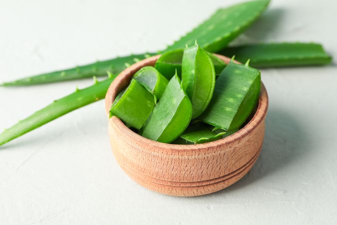 Aloe vera leaves and slices on white table, space for text and closeup. Natural treatment