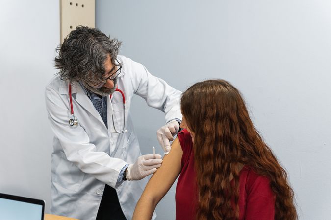 Doctor putting patch on arm of patient after injection
