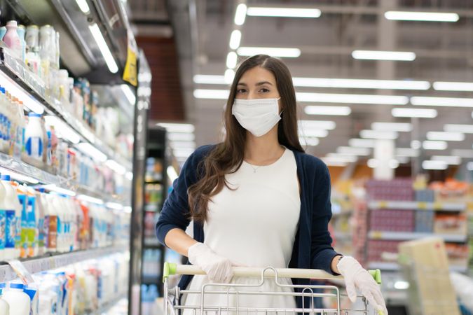 Woman in surgical mask pushing grocery cart