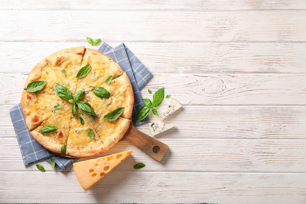 Towel, board, cheese pizza with basil on wooden background, copy space