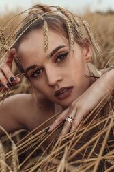 Portrait of young woman with purple make-up in wheat field