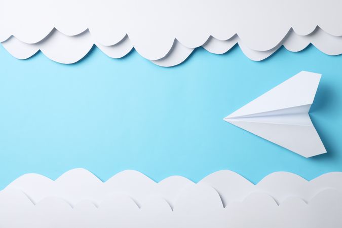 Paper clouds and plane on blue background. Travel