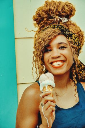 Vertical shot of happy Black female smiling with an ice cream cone in the sun, copy space