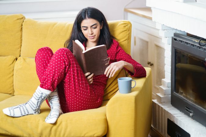 Female relaxing in red pajamas reading at home with book