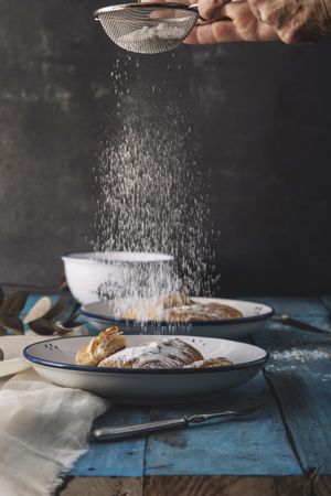 Faceless baker cooking sweet rolls on wooden table