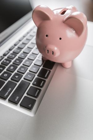 Piggy Bank Resting on Laptop Computer