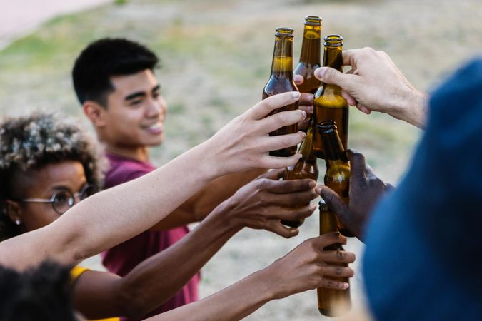 Group of multiracial friends toasting with bottles of beer