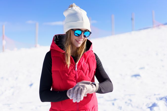 Woman in red snowsuit checking her watch on snowy mountain