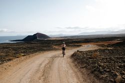 Back of female biking on Lanzarote dirt road