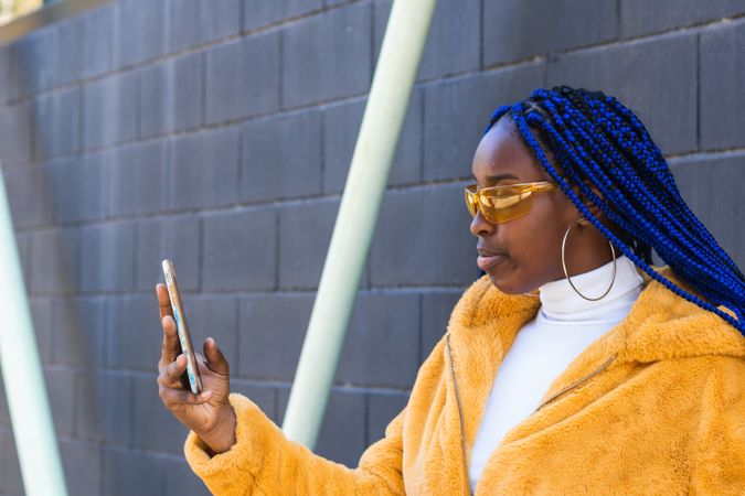 woman in trendy outfit browsing cellphone in city