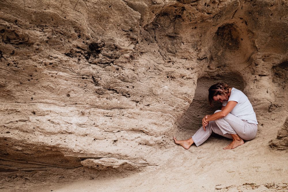 Barefoot woman meditating in rock cavity