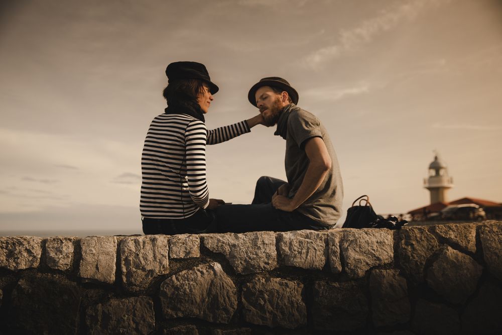 Man and woman on stones near lighthouse