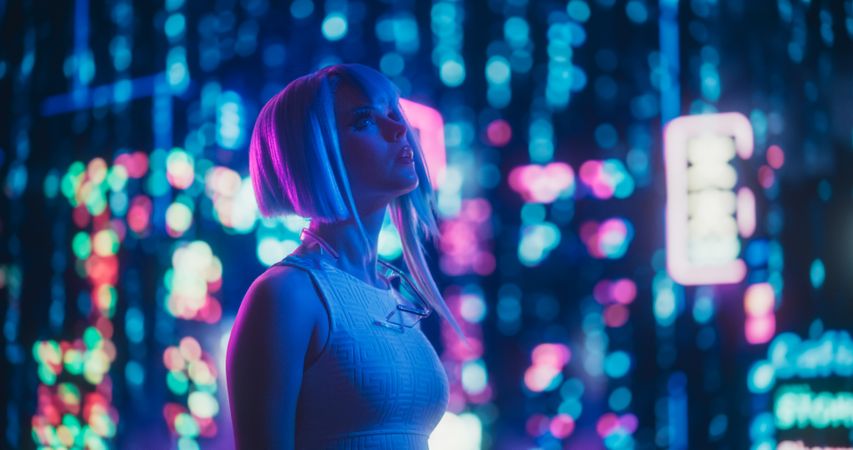 Portrait of an Excited Young Female with Blue Hair Looking Up on a Futuristic Urban Center with Neon Lights and Artificial Intelligence Technology