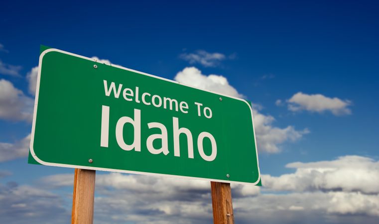 Welcome To Idaho Green Road Sign Over Blue Sky with Some Clouds.