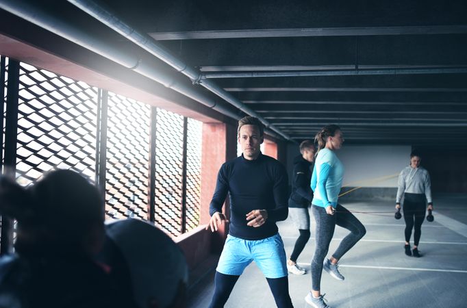 Group of people doing circuit training near a window in a parking garage