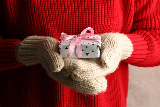 Young woman holding gift box with pink bow, close up