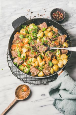 Braised beef stew with potatoes, carrots and parsley, with wooden spoon