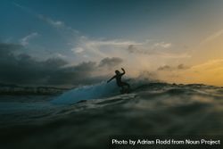 Silhouette of surfer riding a wave at dusk 0yW7q4