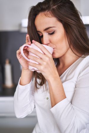Woman drinking from cup in kitchen