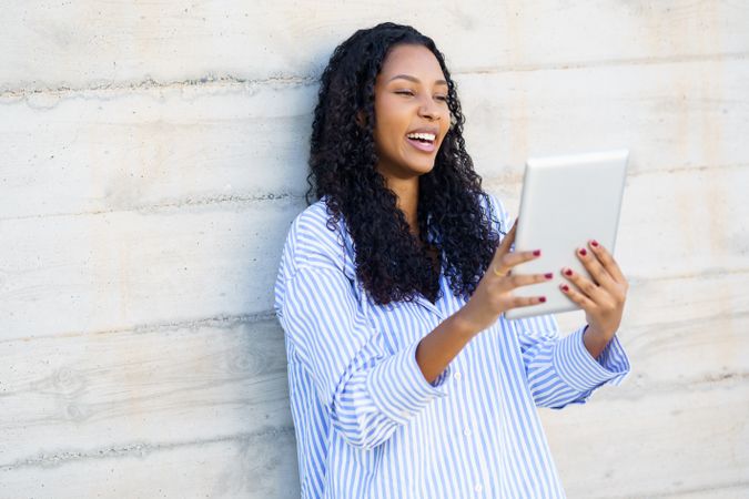 A young woman happily engages with digital content on her tablet in a stylish setting