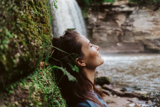 Woman leaning beside waterfall