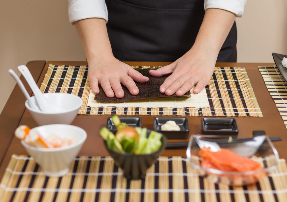 Hands of chef ready to prepare sushi rolls, with fresh ingredients in the foreground