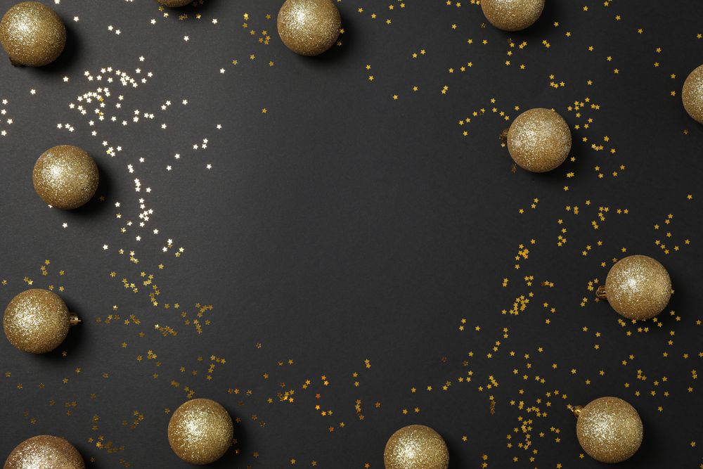 Christmas balls and glitter on dark background, top view