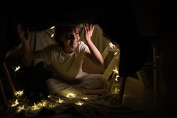 Happy boy sitting in blanket fort