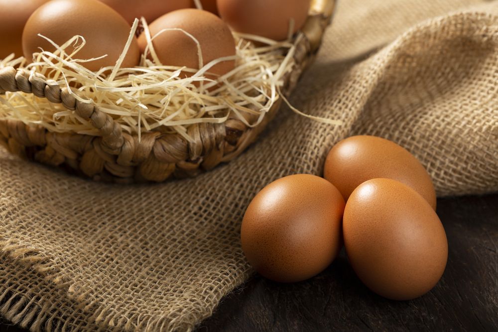 Basket with brown chicken eggs goes up the table.