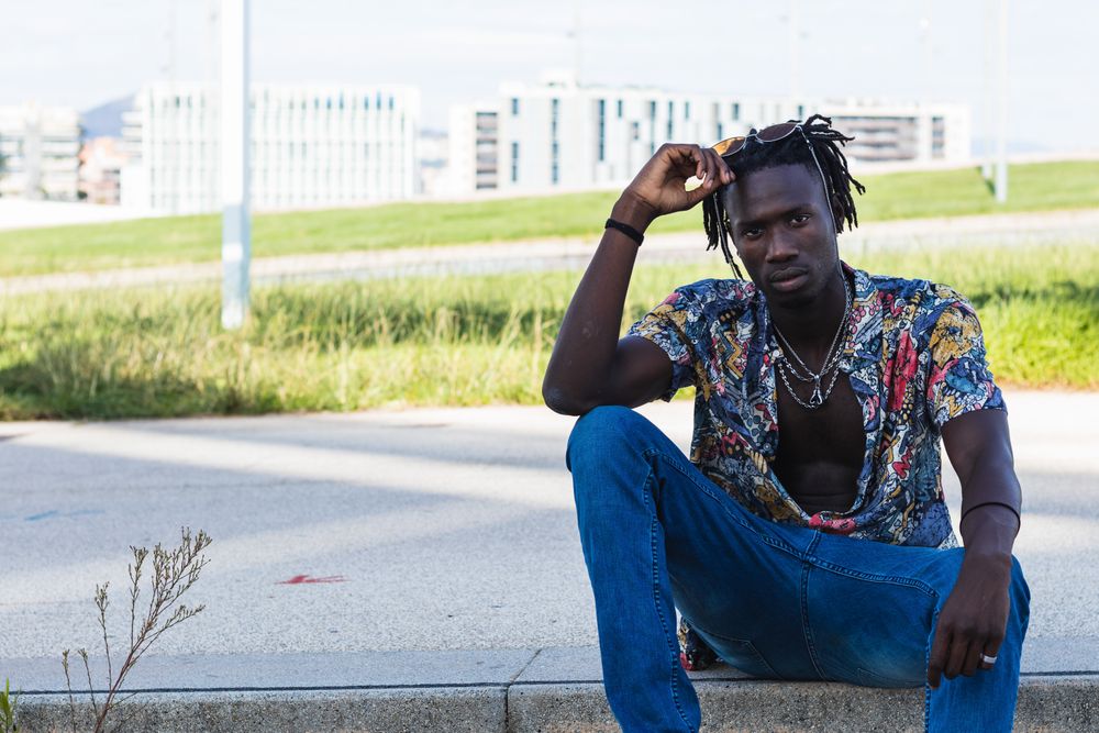 Stylish Black hipster man sitting on stairs in city