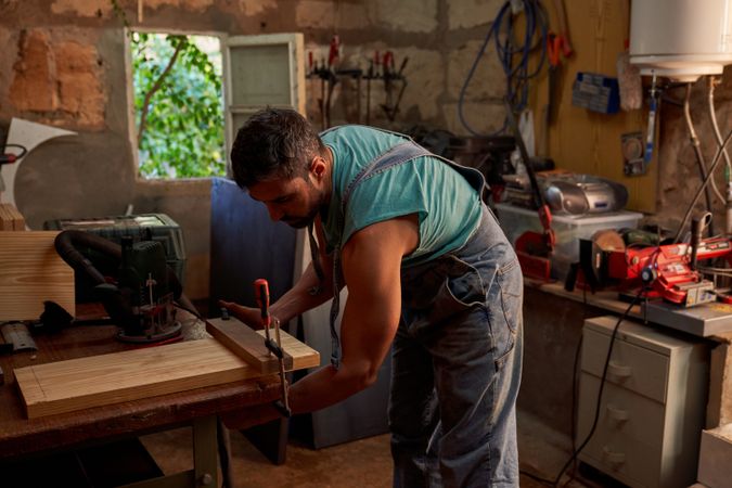 Woodworker using clamp on wooden board