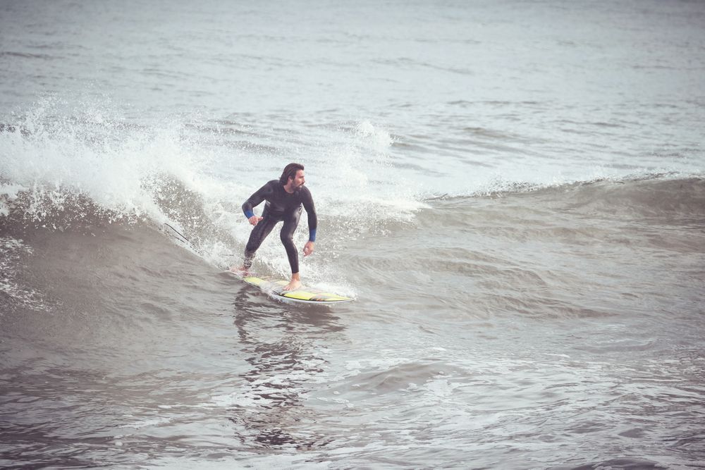 Surfer in wetsuit riding on wave on surfboard in ocean
